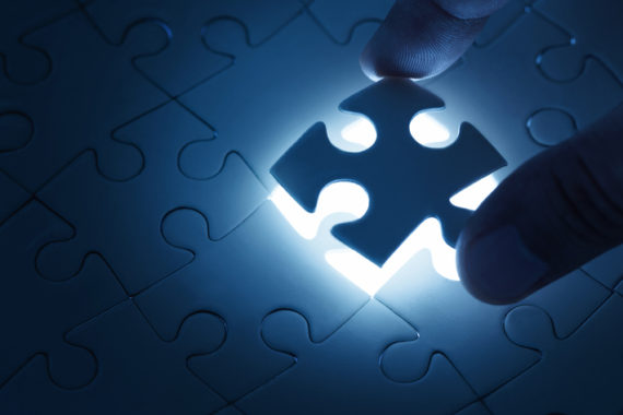 A glowing puzzle piece is being placed into a nearly completed puzzle